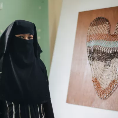  Rohingya-netwever Nuru Sabar naast haar kunstwerk van tarobladeren