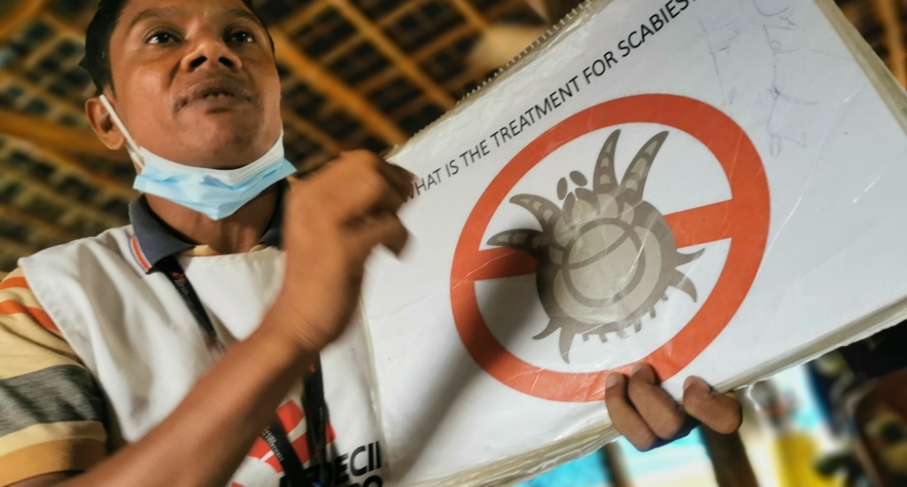 Ali, MSF-vrijwilliger in gezondheidsbevordering voor de gemeenschap, geeft patiënten voorlichting over schurft in de wachtkamer van de kliniek. 